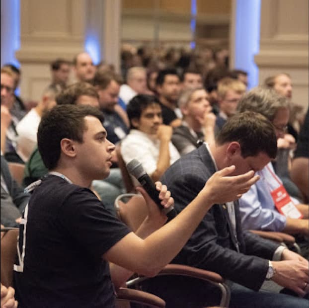 person raising hand at conference